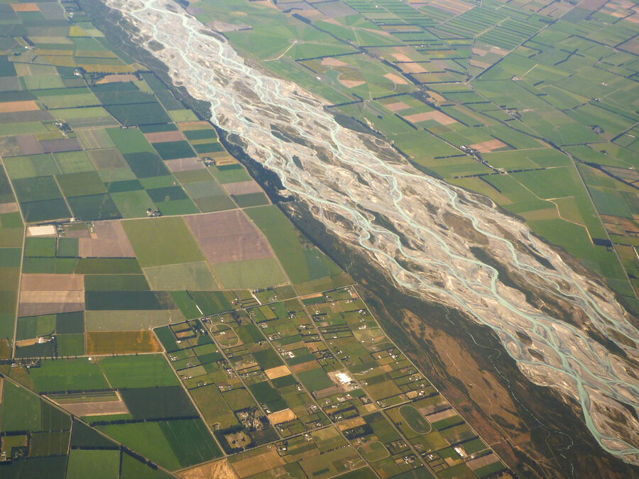 Aerial view of a braided river fanning into many channels across farmland, standing in for how funds fan out across a traced blockchain graph